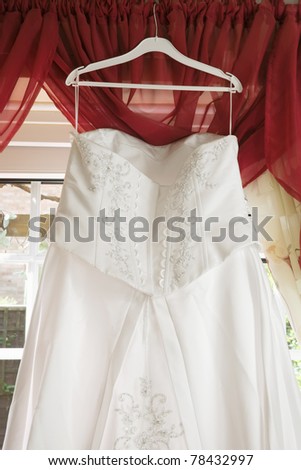 white Wedding dress hanging from a curtain pole