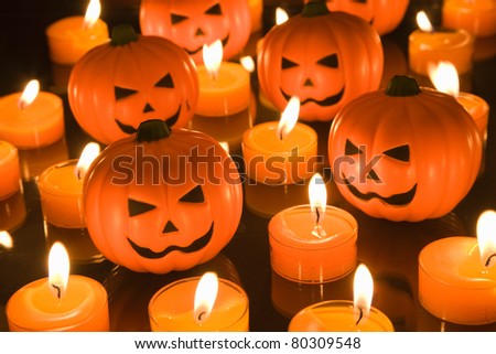 Small Halloween toy Pumpkins surrounded by orange tealight candles
