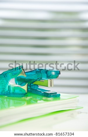 green stapler,staple remover on a green folder,
