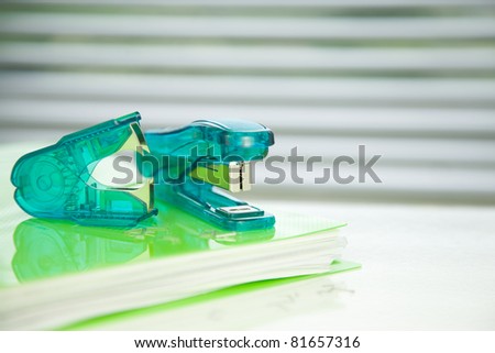 green stapler,staple remover on a green folder,
