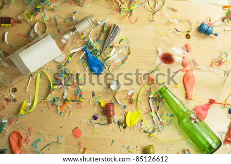 Over head shot of a wooden floor after a party celebration with empty bottles,wine glass and party decorations,