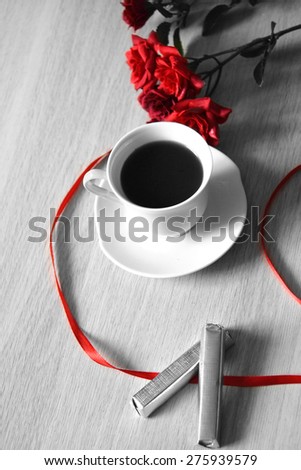 cup of coffee with red ribbon and roses on the table
