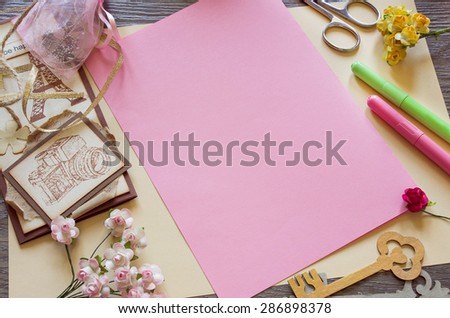 Top view of  paper roses and a pink sheet of paper. Making handmade cards