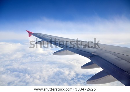 Wing of an airplane flying above the clouds. people looks at the sky from the window of the plane, using air transport to travel or go home
