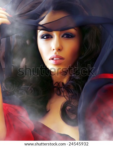 Young beautiful sexual woman in smoke clubs slightly opens a veil, showing the well-groomed person