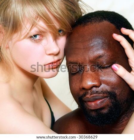Young beautiful blond woman embraces a head of the black man