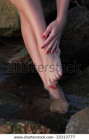 stock photo Beautiful slim feet and hands of the young girl on seacoast 