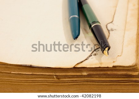 Burn corner of paper of old book and pen