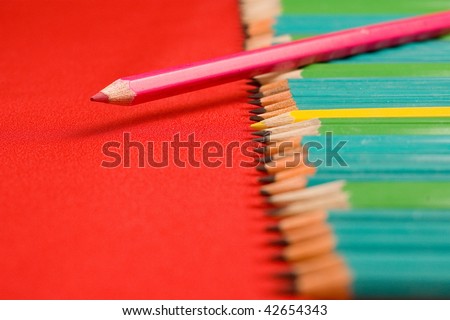 A lot of pencils on red backgrounds, shallow depth of field - focused on yellow pencil in middle of groups