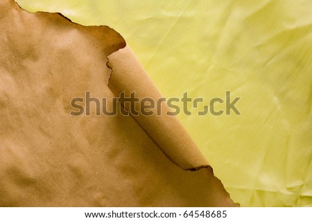 Burnt parchment rolled at corner on wrinkled yellow textile