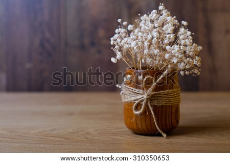 Dried flowers in a wooden vase with a rope on a wooden table. Vintage background.