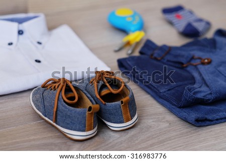 Fashion trendy look of baby clothes and toy on the wooden floor, baby fashion concept. Little boy clothes set.