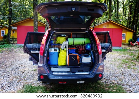 Travel and camping luggage packed in the car trunk. Outdoor wanderlust items. Outdoor, adventures and travel suv.