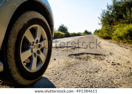 Off-road car wheels on damaged road, cracked asphalt blacktop with big holes, Ukraine. Tire on bad tarmac road. Outdoor, adventures, expedition, and travel suv. Close-up car tyre tracks.