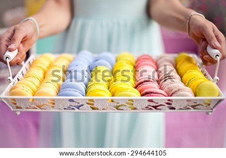 Hand holding tray of colorful macaron