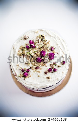 Cream chocolate cake with dry tea rose and pistachio nuts decor