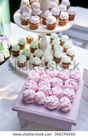 Zefir or marshmallow roses on a wooden stand as part of sweet dessert table or candy bar. Wedding party. Natural light