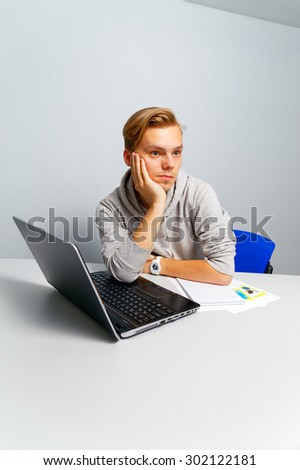 Office worker thinking. Blonde sitting at a table in front of a computer.