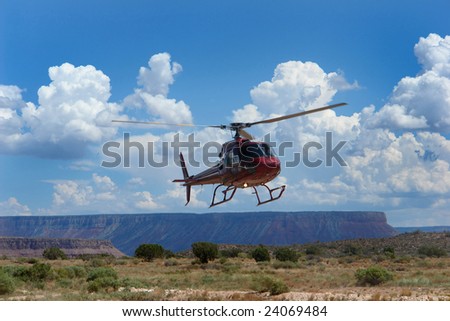 The helicopter lands in the desert against the backdrop of the canyon
