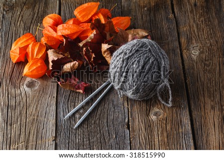 Clew of gray homemade wool yarn with needle. Rustic wooden background