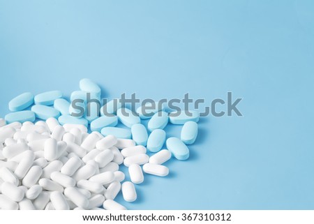 Many blue and white pills and drugs  scattered on blue