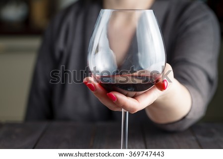 woman drinking alcohol on dark background. Focus on wine glass