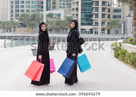 Emirati women walking after shopping carrying a lot of colourful shopping bags