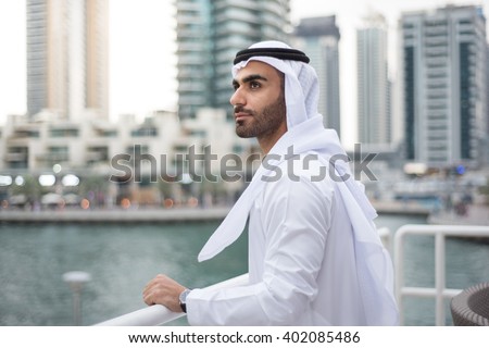 Middle Eastern Arab man standing alone at a terrace in Dubai Marina looking forward