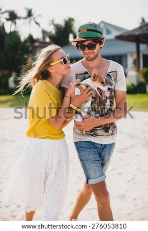 young stylish hipster couple in love holding walking playing dog puppy jack russell in tropical park