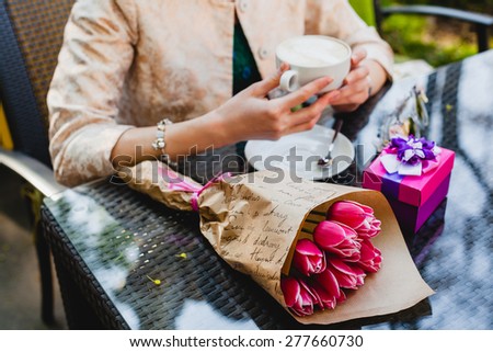 young stylish woman, fashion sunglasses, sitting in cafe, holding drinking cup cappuccino, tulips, happy birthday party, boho outfit, europe vacation, romantic dinner, gift, close up, detail