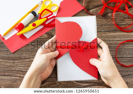 The child holds Mother's Day or Valentine's Day gift - card heart. Handmade. Project of children's creativity, handicrafts, crafts for kids.