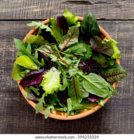 Fresh green mixed salad in a bowl on a dark wooden table