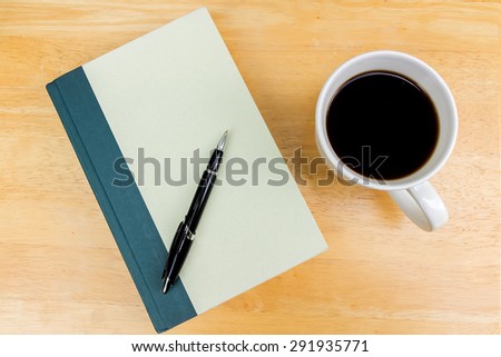 cup of coffee  with a book and a black on a wooden table in the garden