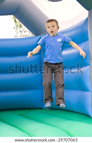 Portrait of a cute six year old boy jumping on a bouncy castle moonwalk