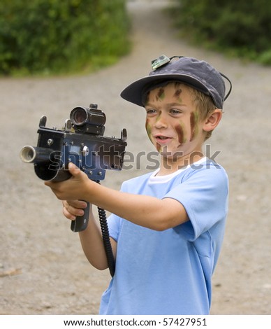 A young boy with camouflage paint on his face preparing to play war games