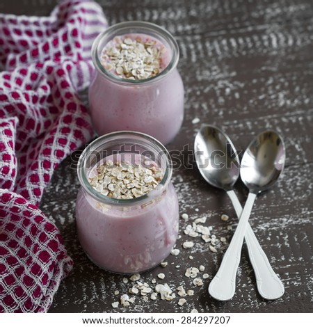smoothie with strawberries and oat flakes in a glass jar on a dark brown wooden background