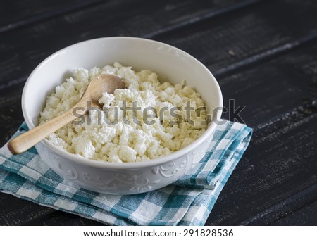 cottage cheese in a white bowl on a dark wooden background