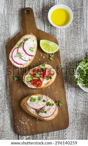 sandwiches with soft cheese, cherry tomatoes and radishes - healthy snack on a light wooden background