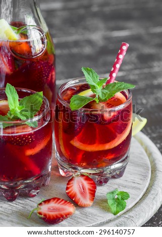 strawberry lemonade with lemon and mint in glass beakers on a light surface