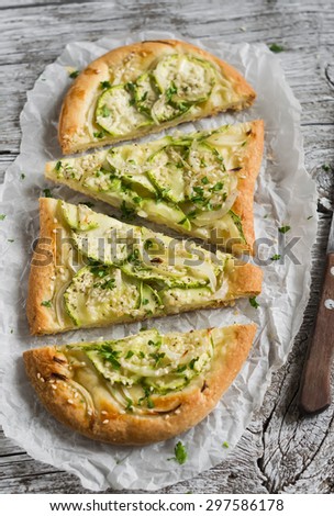 pizza with zucchini, onions and mozzarella on a light wooden background