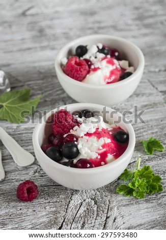 cottage cheese with berries and berry puree in a white bowl on a light wooden background