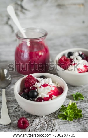 cottage cheese with berries and berry puree in a white bowl on a light wooden background, healthy Breakfast, snack