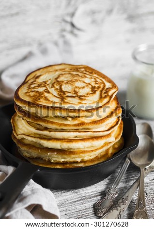 pancakes with honey in a pan on a light wooden background