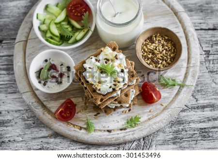 healthy snack - rye crackers, cottage cheese with cucumber and flax seed on a light wooden background