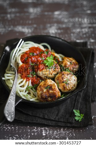 spaghetti and chicken meatballs with tomato sauce in a pan on a dark wooden background