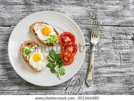 toast with soft cheese and quail eggs on a white plate on a light wooden background