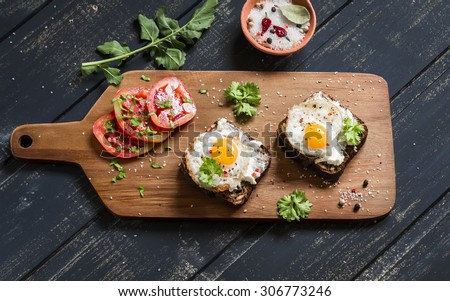 toast with feta cheese and fried quail egg, fresh tomatoes on a dark wooden surface - a healthy Breakfast or snack