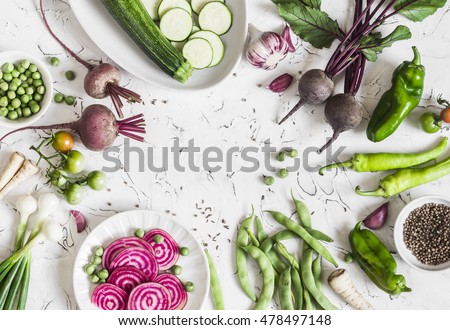 Fresh raw vegetables - beets, green peas and beans, zucchini, peppers, onions, garlic, spices on a light background. Cooking background, space for text. Top view