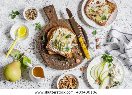 Toast with cheese, pear, honey and nuts. Delicious breakfast or snack on a light background, top view.