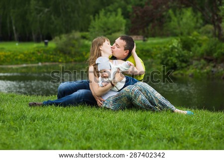 Happy family with a baby resting in summer park on the lake